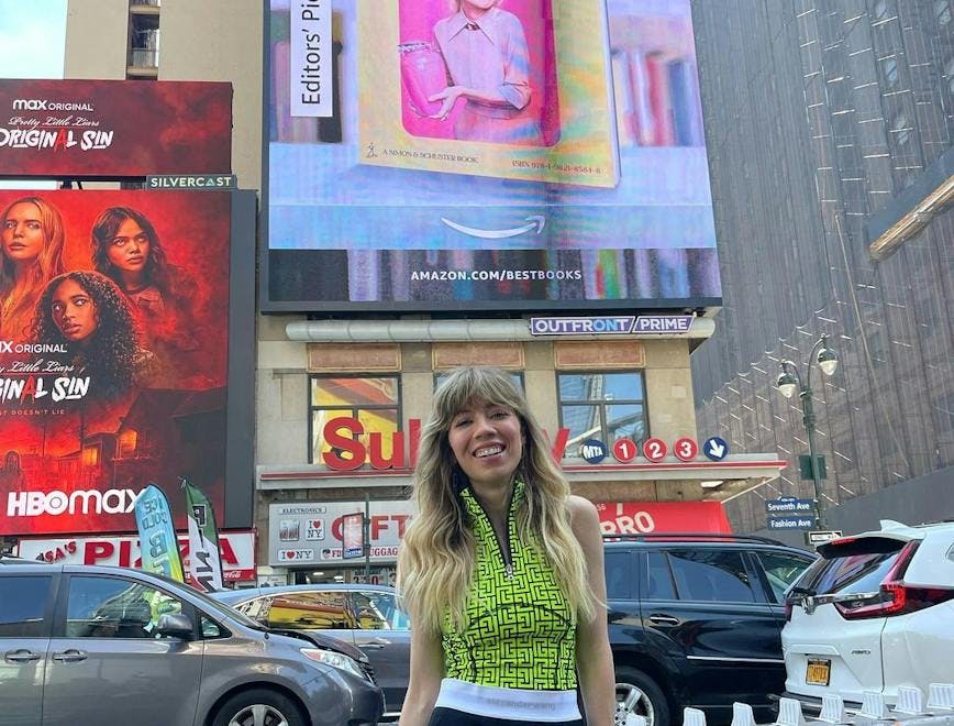 Jennette McCurdy standing under a billboard of her memoir “I’m Glad My Mom Died.”
